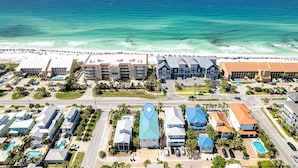 Vista aérea de un hotel costero con varias edificaciones, una playa y un área de piscina.