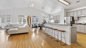 Un amplio espacio de sala con un sofá grande, una mesa de comedor y taburetes de bar.