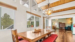 Un comedor amplio con una mesa y bancos de madera, ventanas grandes y vistas al exterior.