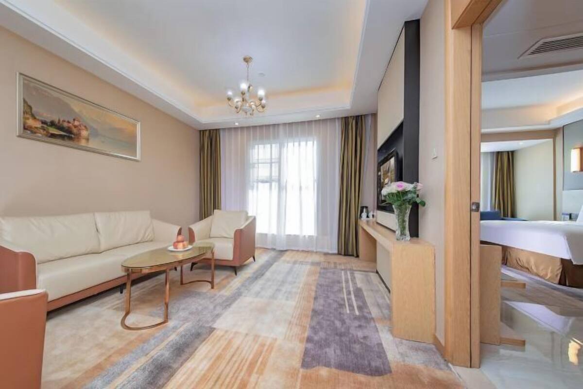 Ein modernes Hotelzimmer mit Sofa, einem kleinen Tisch, einem Spiegel und einem Fernseher.