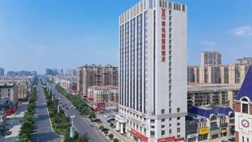 Un edificio alto con varios pisos, rodeado de otros edificios, y un cielo despejado.