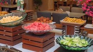 Een buffet tafel met verschillende soorten eten, zoals schalen met watermeloen en kaas, en schalen met hapjes.