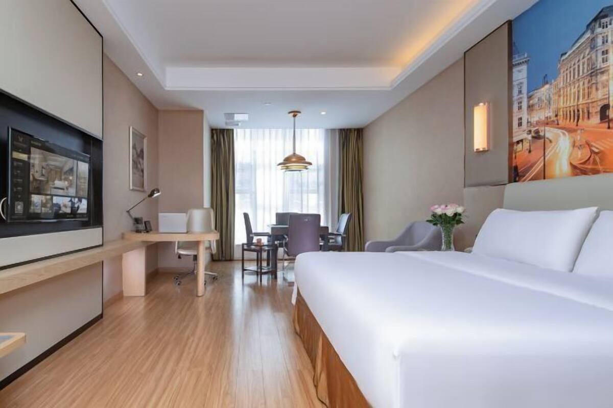 Ein Hotelzimmer mit einem großen Bett, einem Schreibtisch mit Stuhl, einem Fernseher und einem Bild an der Wand.