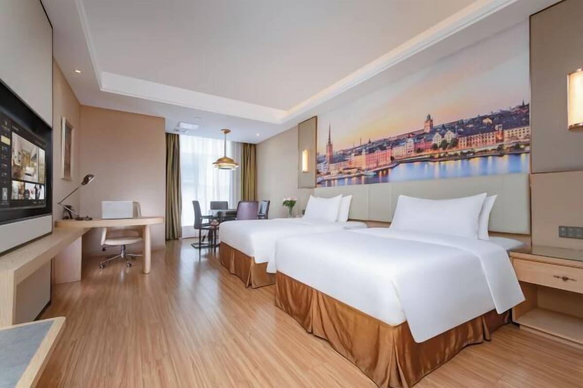 Ein Hotelzimmer mit zwei Betten, einem Schreibtisch, einem Stuhl und einem großen Fenster.
