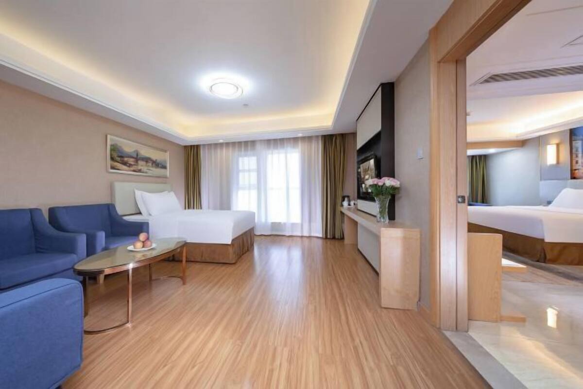 Ein Hotelzimmer mit Bett, Sofa, Fernseher und Schreibtisch.