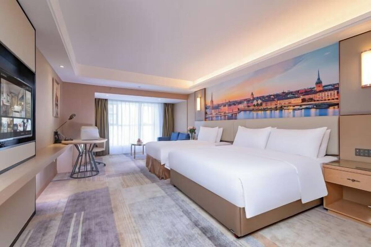 Ein Hotelzimmer mit einem großen Bett, einem Schreibtisch, einem Sessel und einem Fernseher.