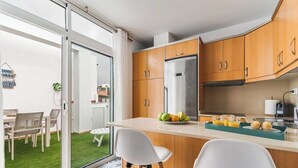 A modern kitchen with wooden cabinets, a stainless steel refrigerator, and a breakfast bar.