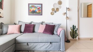 A modern living room with a grey sectional sofa, decorative wall art, and a cactus plant.