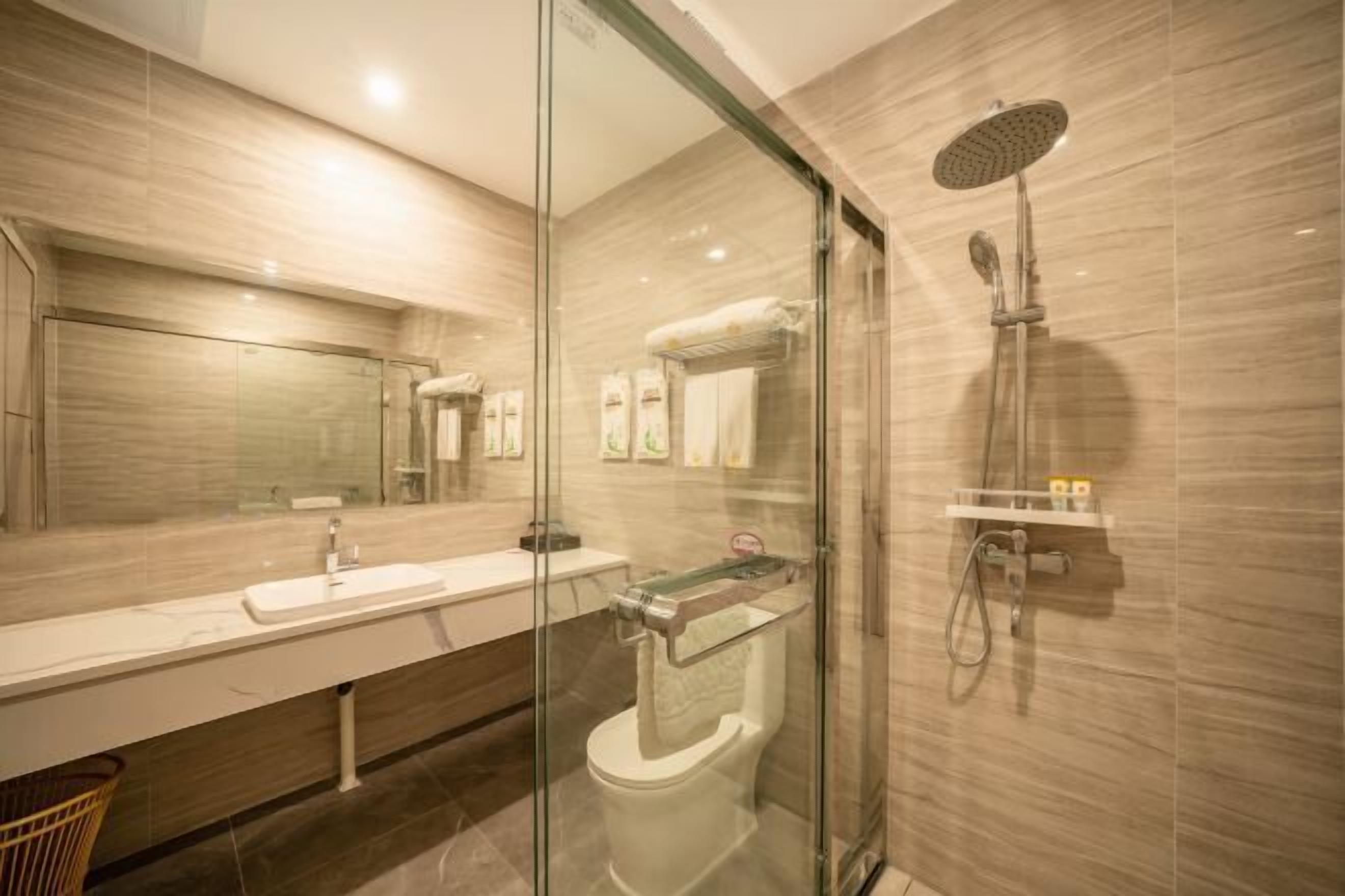 A modern bathroom with a glass shower enclosure, a white sink, and a mirror.