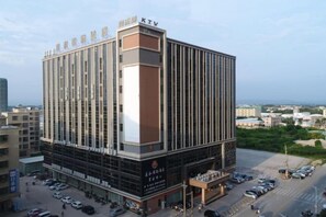 Un hôtel à plusieurs étages, avec une enseigne bien visible au sommet, une entrée au niveau du sol et un espace de stationnement à l’avant.