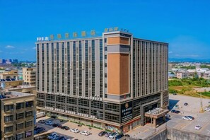 A multi-story hotel with a prominent vertical design, a central entrance, and a parking area in front. - Maomingjia International Hotel (Dianbai Wanda Plaza Branch) (Maoming)