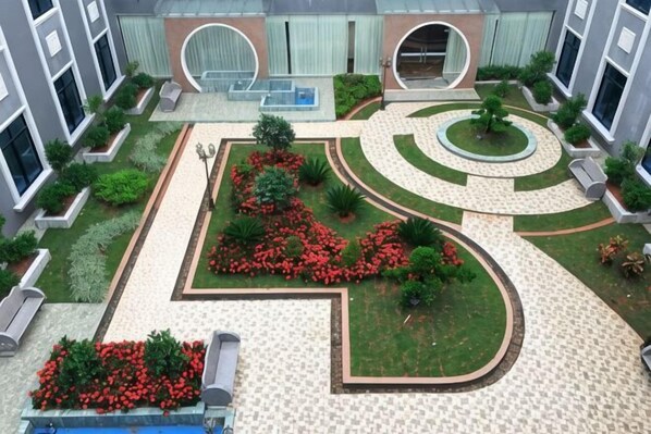 Un patio con un jardín circular central, senderos y zonas de estar.