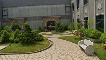 A courtyard with a tiled walkway, benches, and greenery.