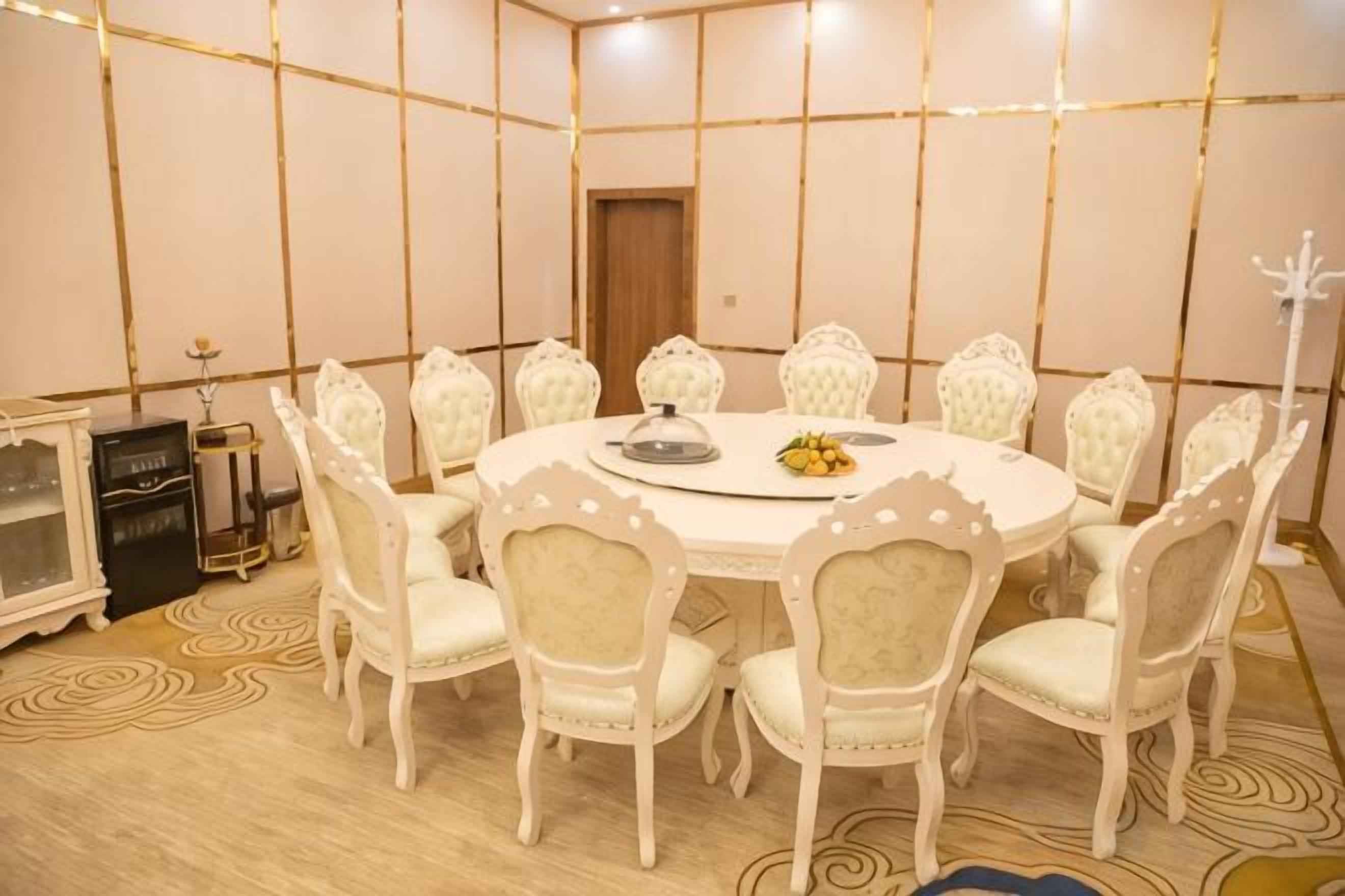A conference room with a round table, white chairs, and a decorative centerpiece.