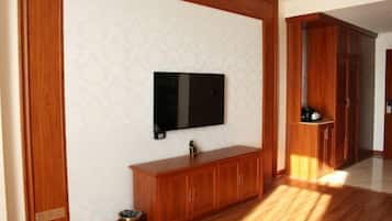 Une pièce avec un meuble en bois, un téléviseur fixé au mur et une poubelle.