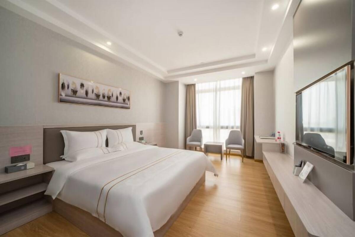 Habitación de hotel con una cama grande, un escritorio con silla, televisor y un cuadro en la pared.