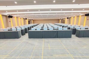 Une salle de conférence avec plusieurs tables disposées en rangées, équipées de microphones et de plaques nominatives.