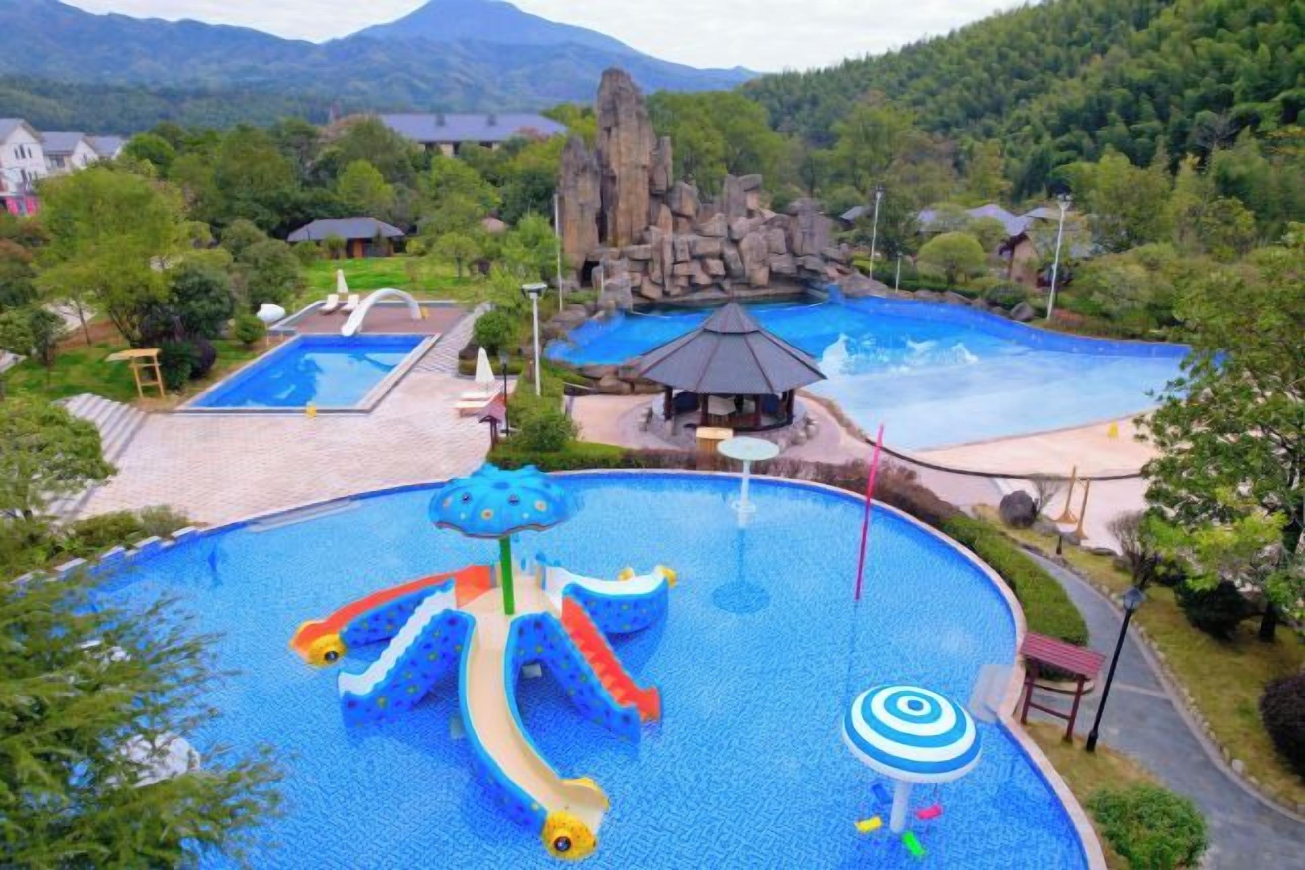 A large outdoor swimming pool with slides and a rock formation in the background.