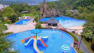 A large outdoor swimming pool with slides and a rock formation in the background.