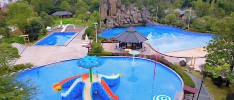 A large outdoor swimming pool with slides and a rock formation in the background.