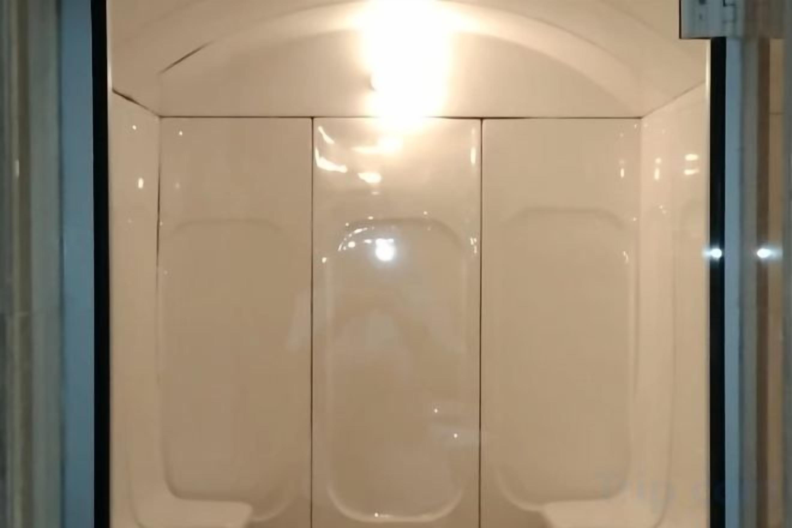 A room with a large mirror, a light fixture, and a door.
