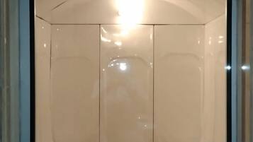 A room with a large mirror, a light fixture, and a door.