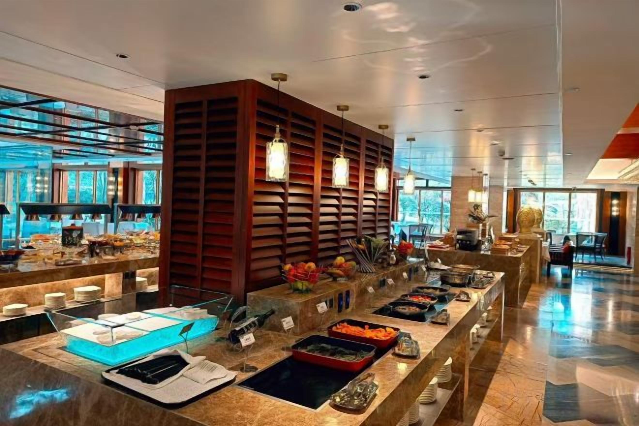A modern hotel buffet with a variety of food options, a seating area, and a large window providing a view of the outdoors.