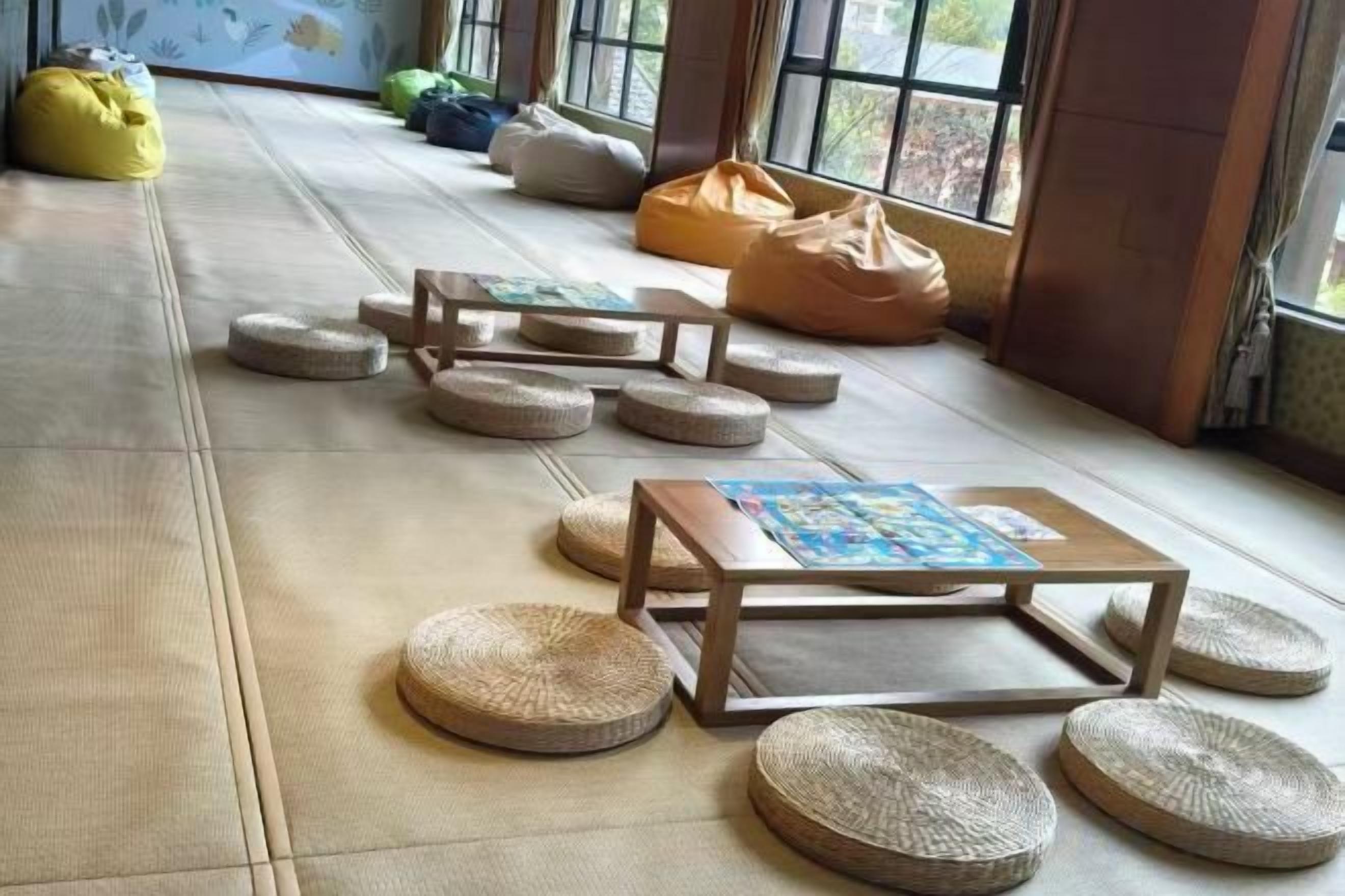 Tatami mats, a low wooden table, and bean bags in a room with large windows.