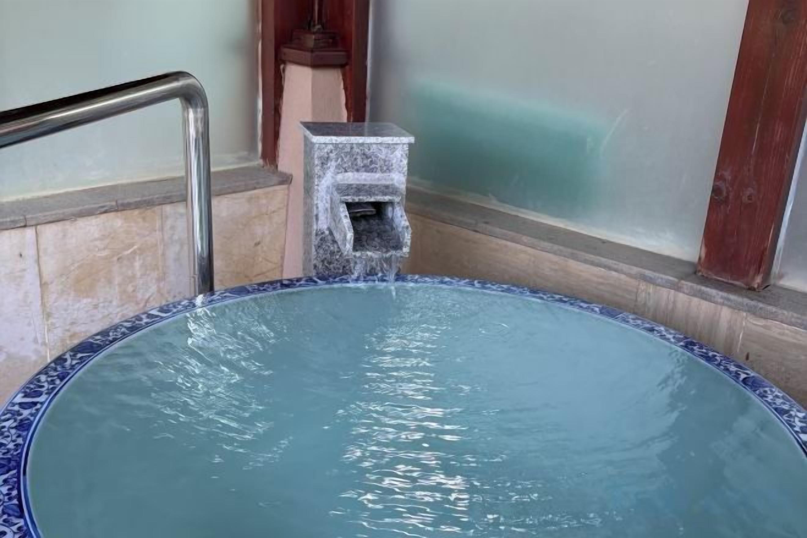 A hot tub with a metal railing and a stone pump.