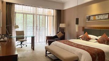 A hotel room with a large bed, a desk, a chair, and a sofa.