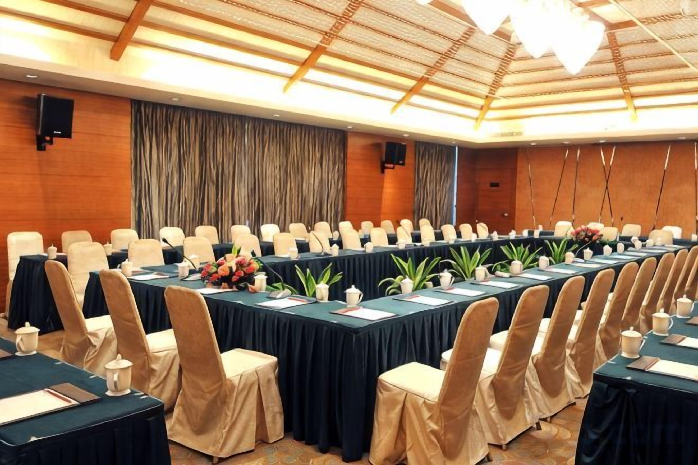 A conference room with a long table, chairs, and floral centerpieces.