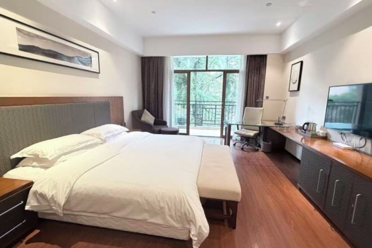 A modern hotel room with a large bed, a desk, and a TV.