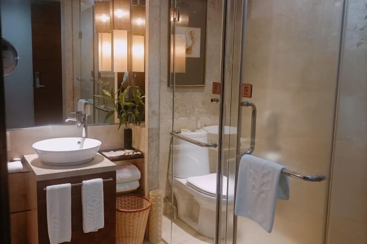 A modern bathroom with a glass-enclosed shower, a sink with a mirror, and a toilet.