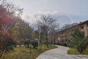 A pathway in a landscaped area with trees and a building in the background. - Wugong Mountain Rongyuan International Hot Spring Resort (Anfu)