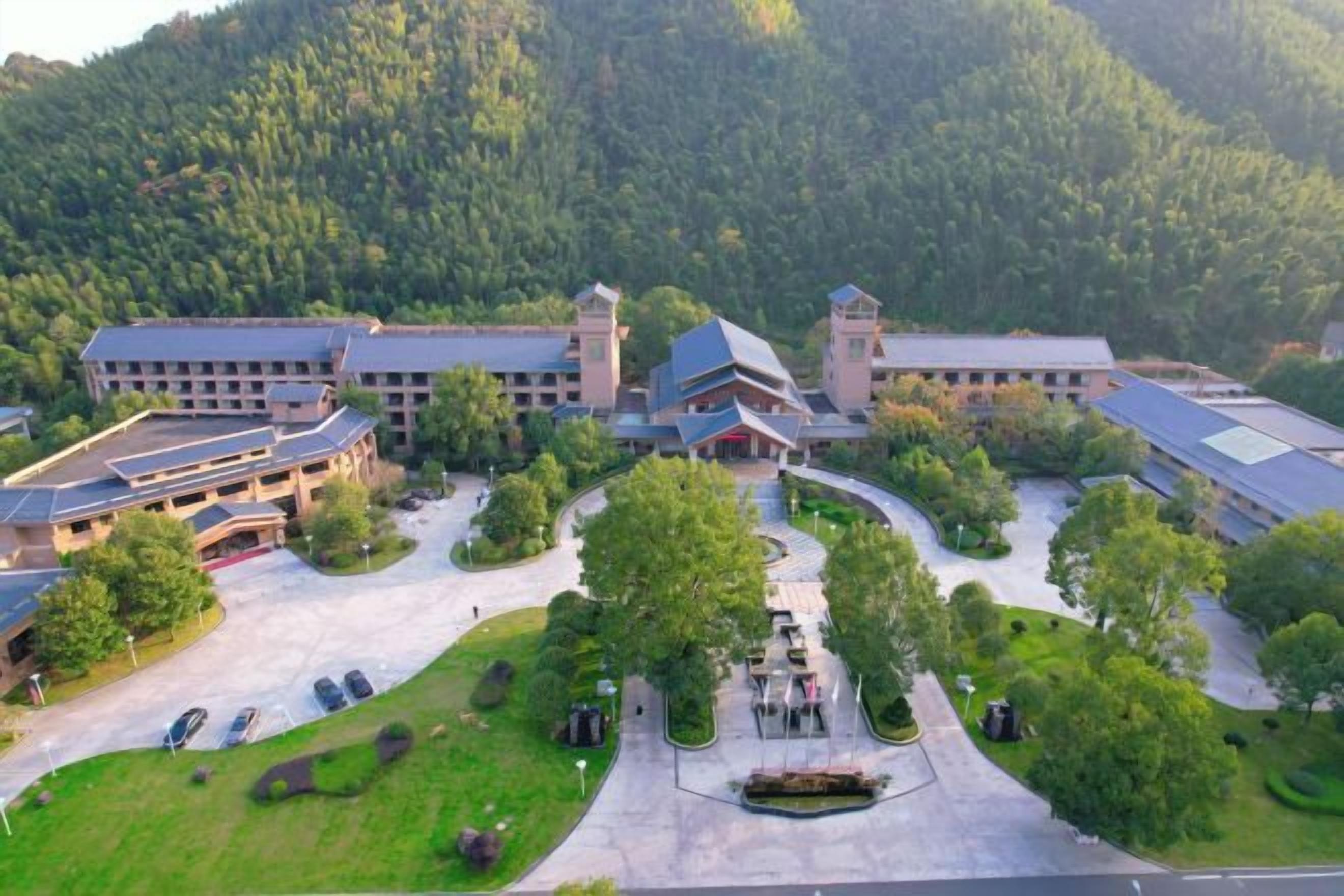 A large hotel with multiple buildings, a central courtyard, and surrounding greenery.