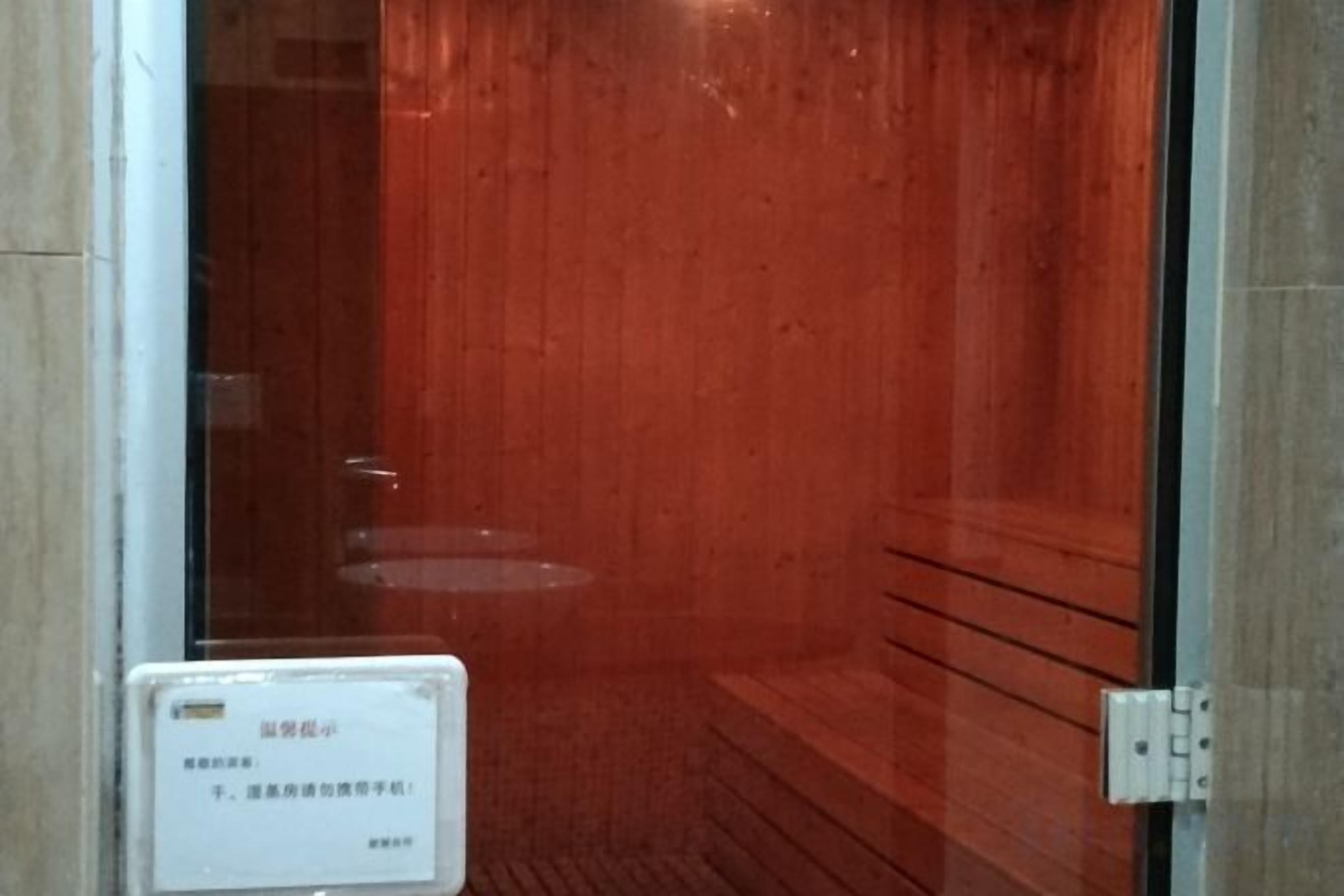 A sauna room with a wooden bench and a glass door.