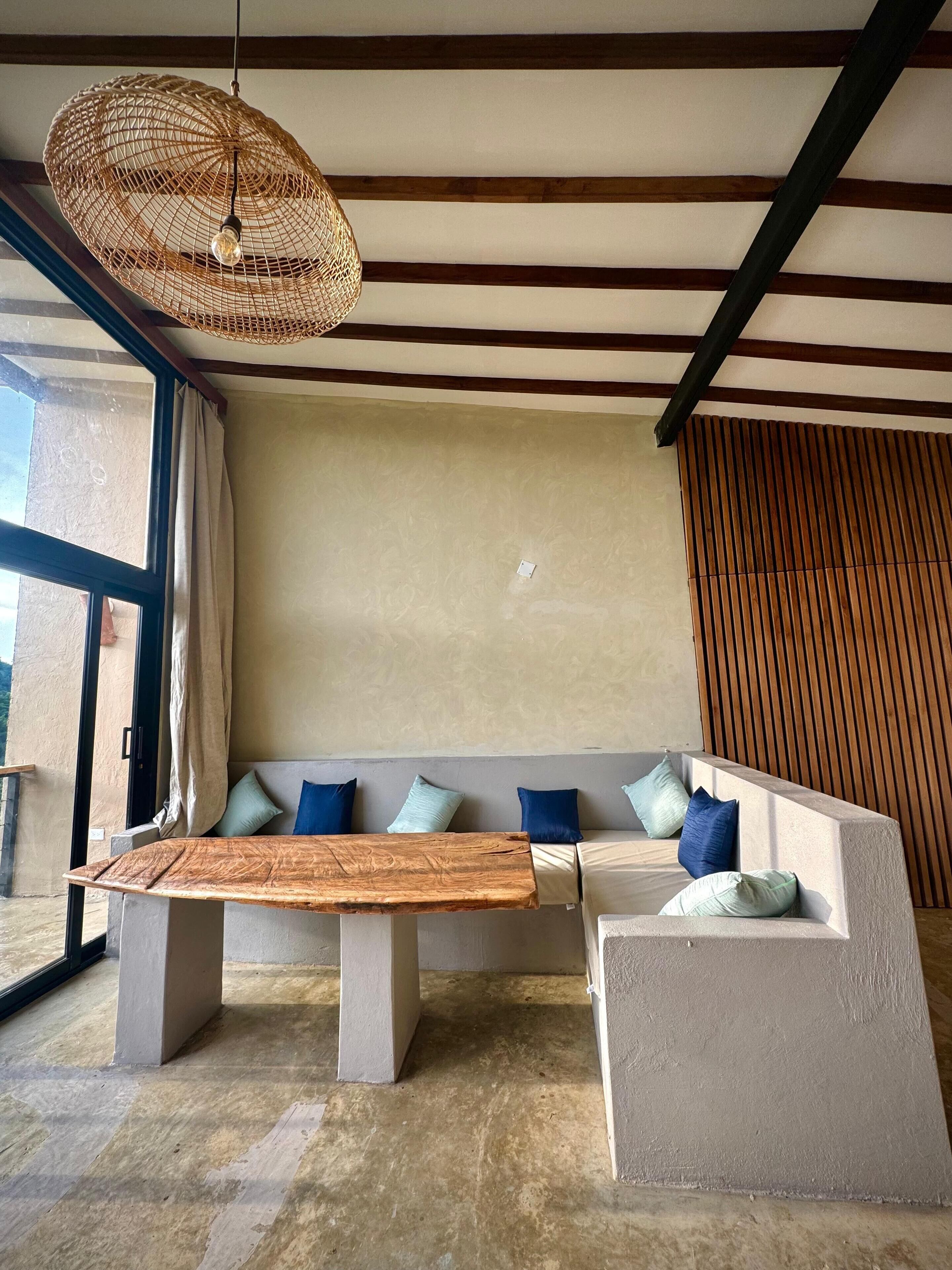 A modern living room with a sectional sofa, a wooden coffee table, and a woven pendant light.