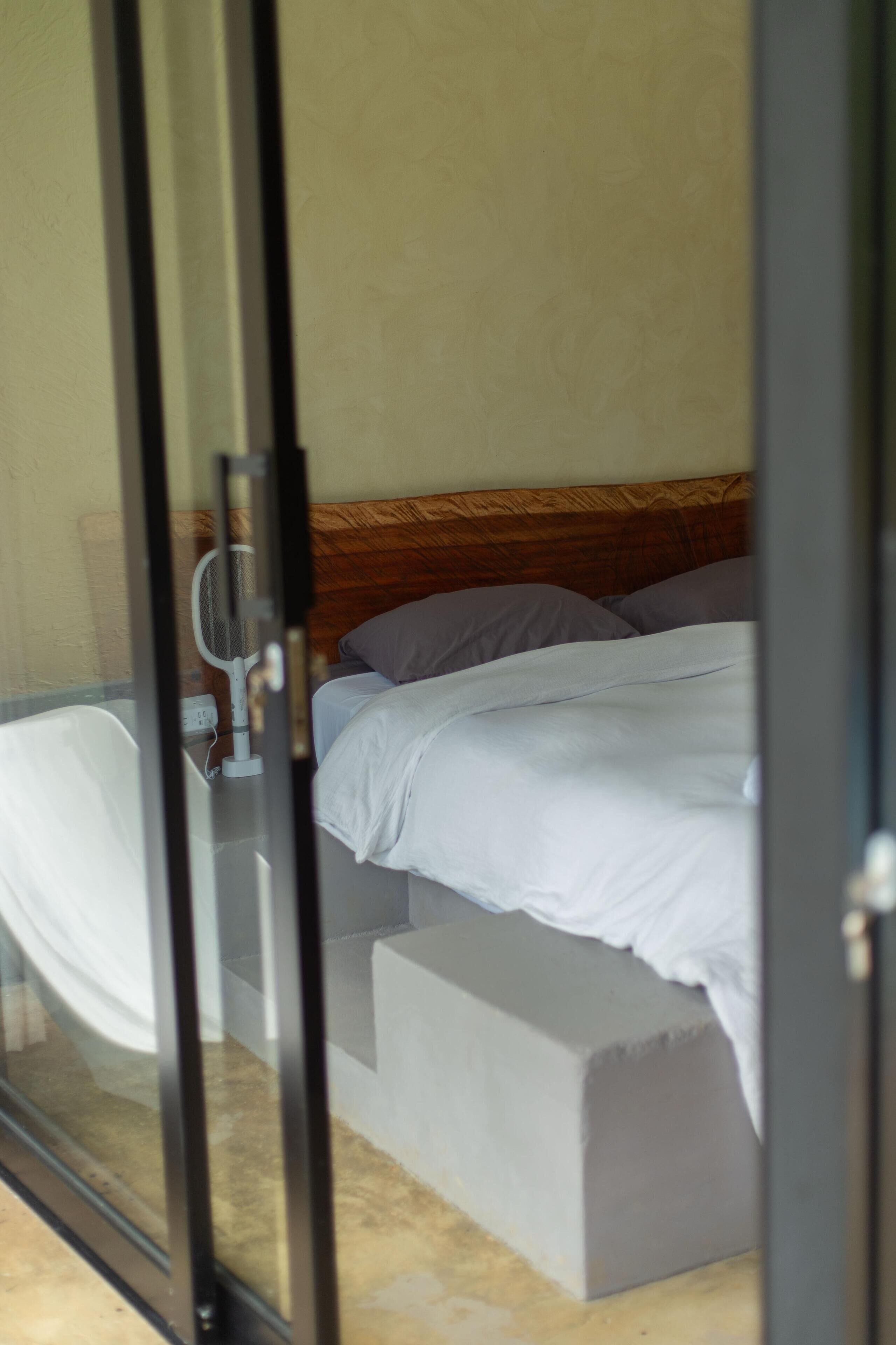 A bedroom with a bed, a bedside table, and a mirror.