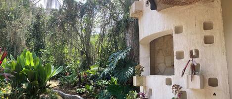 A garden with a concrete wall, potted plants, and a hanging light fixture.