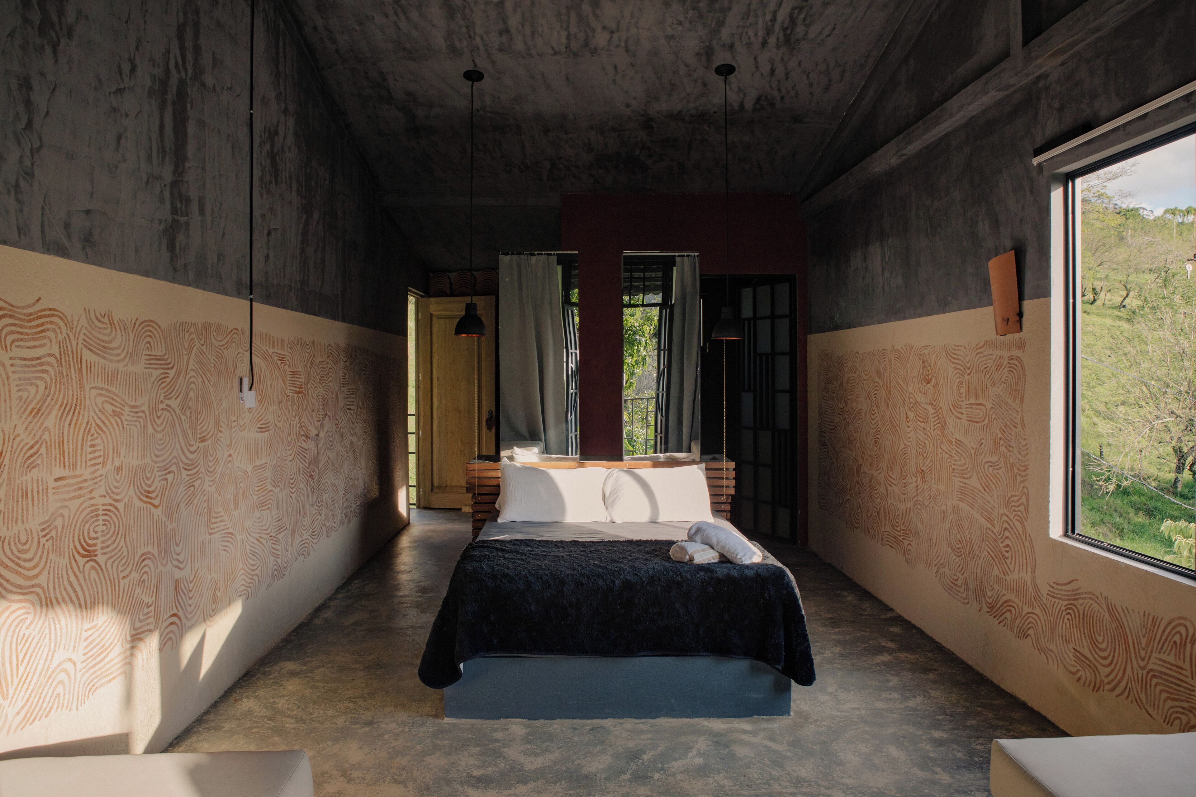 Un dormitorio con una cama grande, una ventana con vistas a vegetación y un diseño de pared estampado.