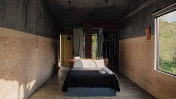 Un dormitorio con una cama grande, una ventana con vistas a vegetación y un diseño de pared estampado.