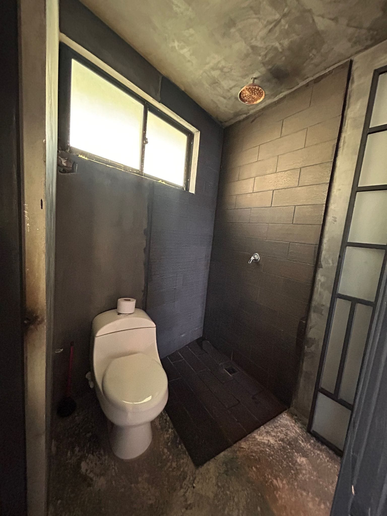 Un baño pequeño y estrecho con inodoro, ventana y zona de ducha.