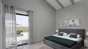 Um quarto moderno com uma cama grande, vista para o exterior, decoração de estrelas na parede e uma cadeira perto da janela.