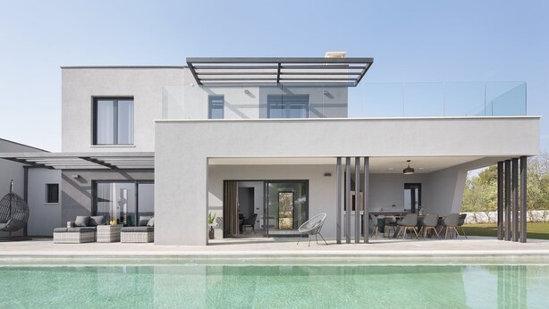 Uma casa moderna de dois andares com varanda de vidro, piscina e área de estar externa.