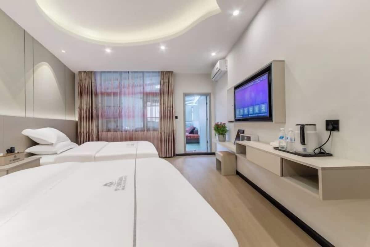 Une chambre d’hôtel moderne avec deux lits, une télévision, un bureau avec une machine à café et une vue sur l’extérieur.