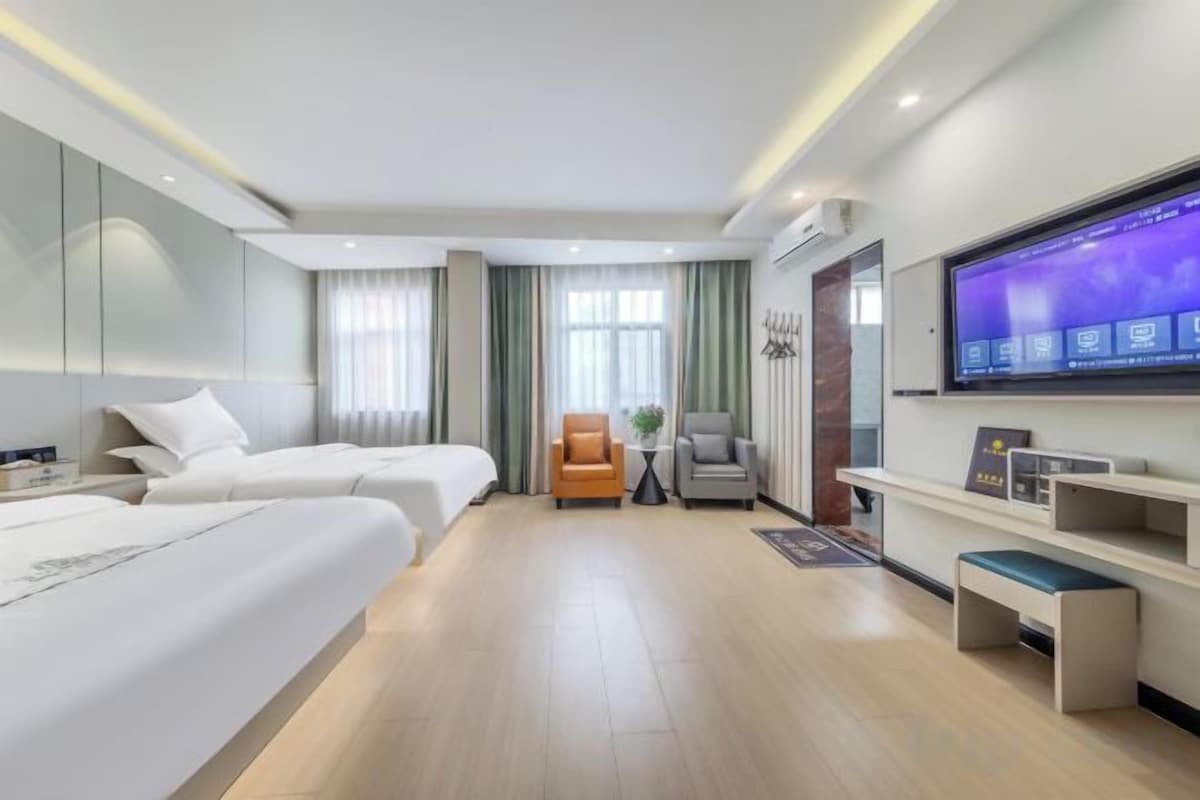 Een hotelkamer met twee bedden, een televisie, een bureau en een stoel.