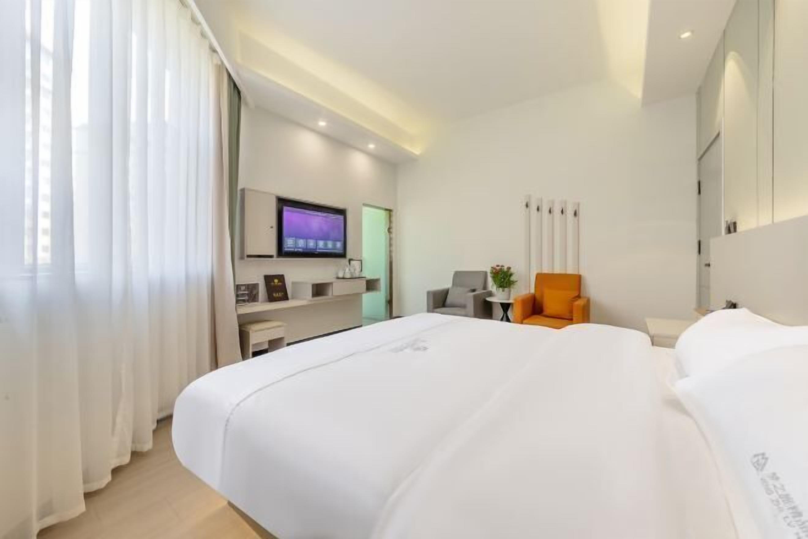 A hotel room with a bed, a TV, a chair, and a desk.