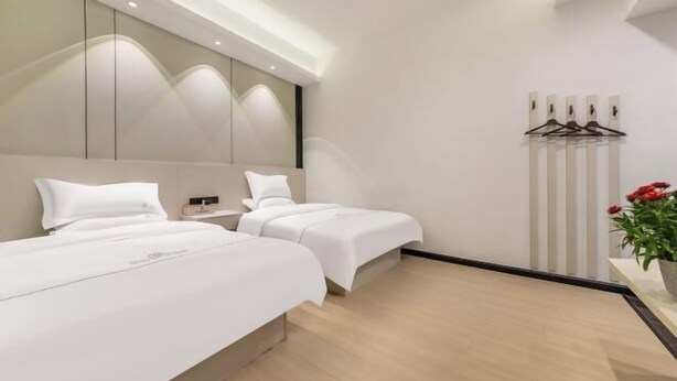 Een moderne hotelkamer met twee bedden, een grote spiegel en een wandlamp.