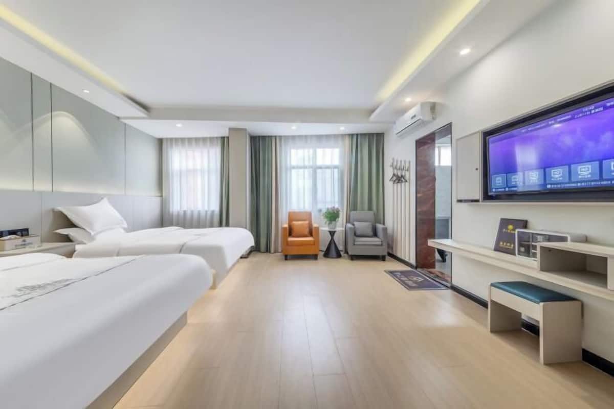 Une chambre d’hôtel avec deux lits, une télévision, un bureau et un coin salon.