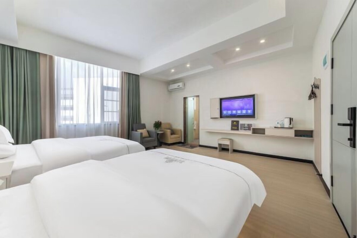 A hotel room with two beds, a TV, a small table, and a sofa.
